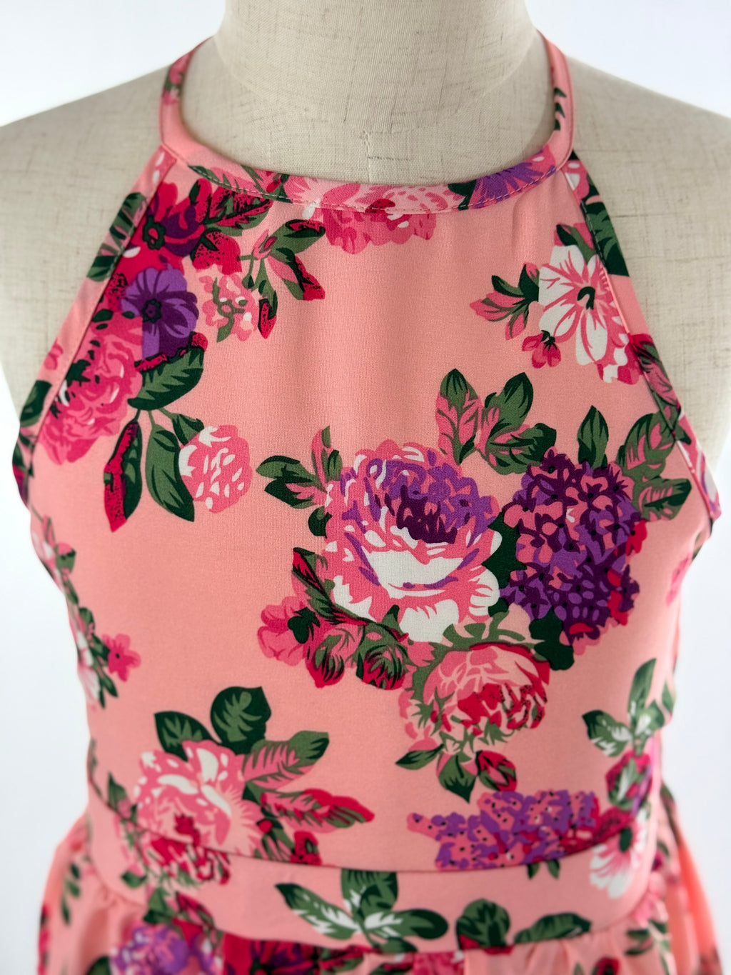 Closeup of front view of pink floral high-low halter neck girls party dress, suitable for birthdays, weddings, parties, photoshoots and graduations