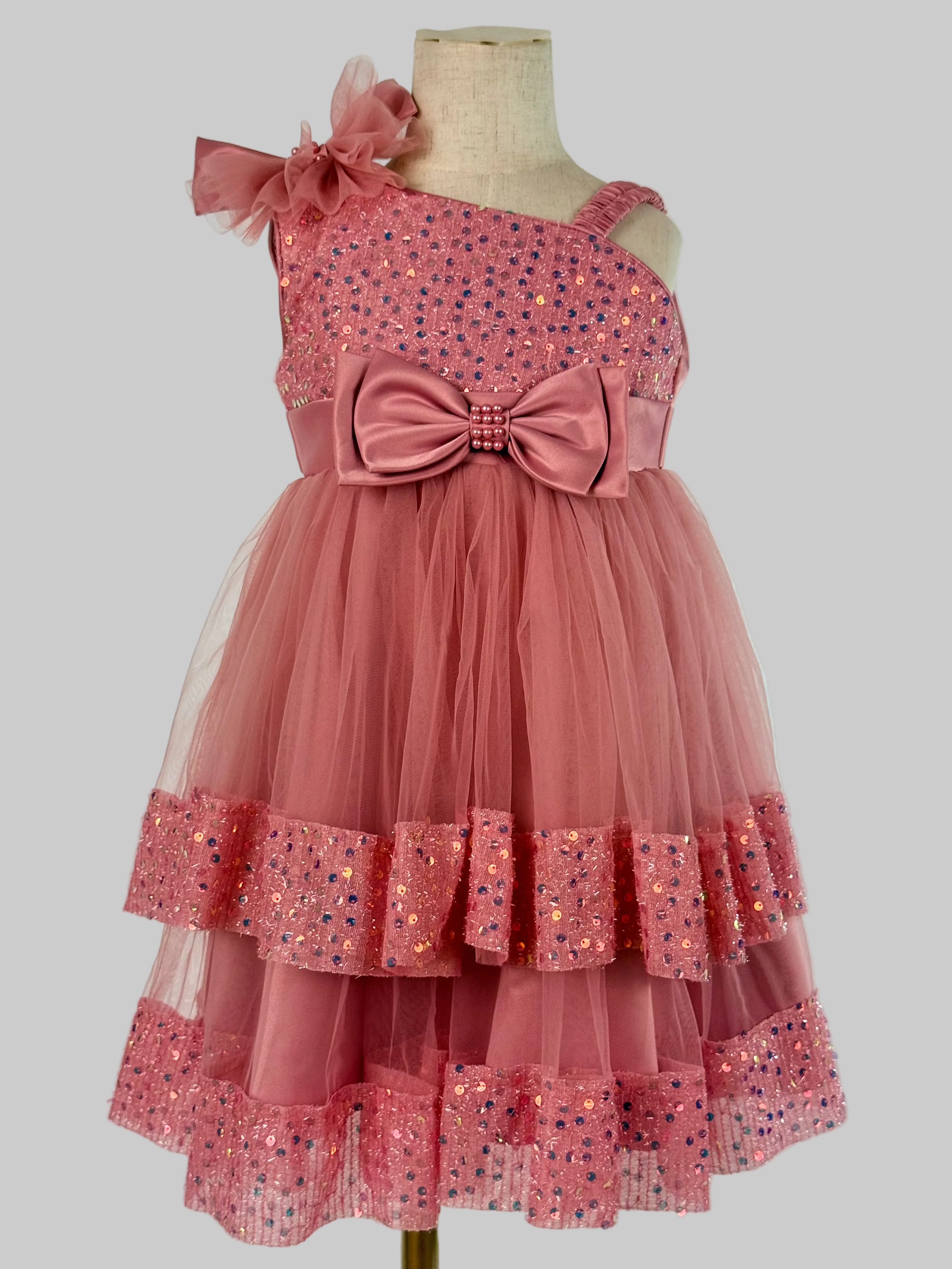 Front view of blush pink tulle sequin one shoulder girls party dress, suitable for  birthdays, flower girls, photo shoots, formal occasions