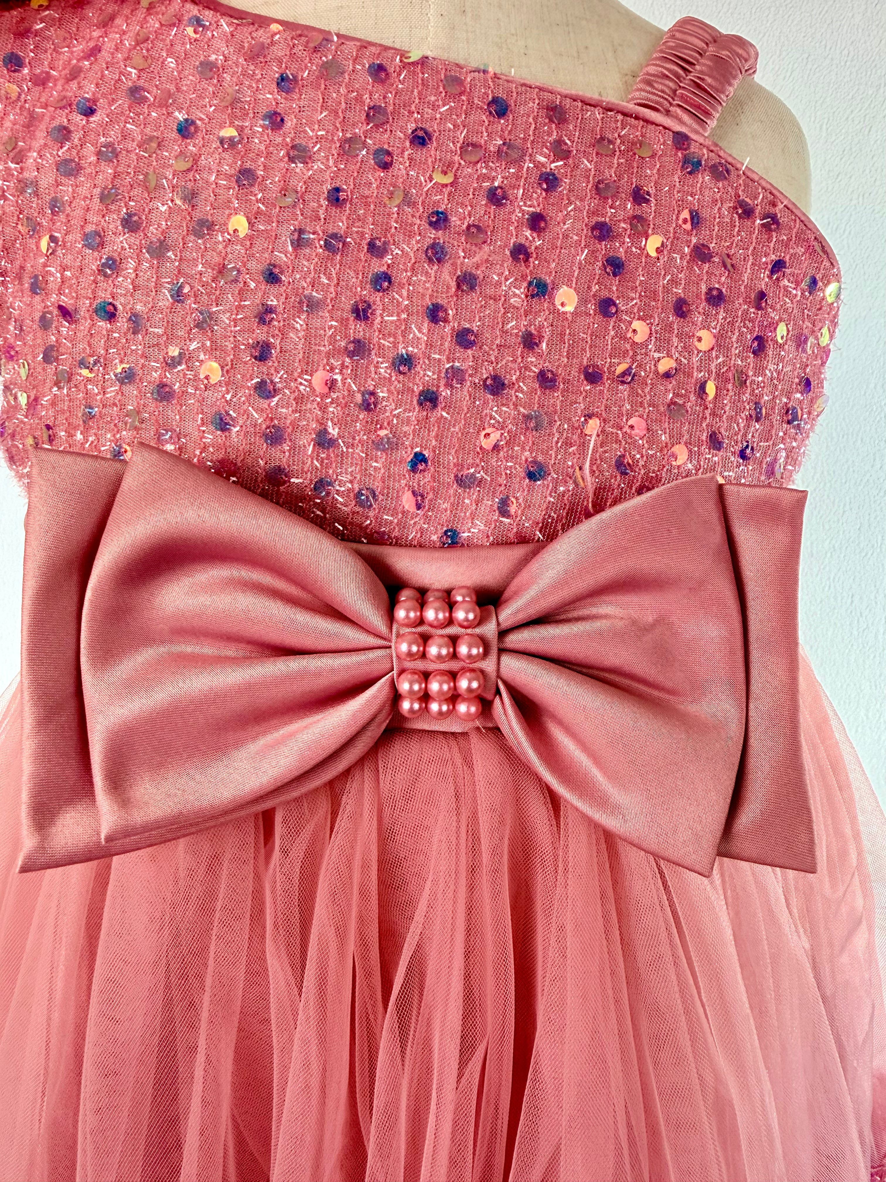 Closeup of blush pink tulle sequin one shoulder girls party dress, suitable for  birthdays, flower girls, photo shoots, formal occasions